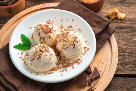 Three balls of creamy ice cream with chocolate chips and mint on a brown background. Refreshing...