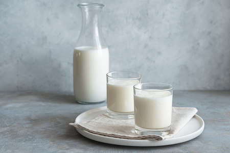 Two glasses and a bottle of fresh milk drink on a gray background. Lassi, kefir, yogurt. Side view, horizontal.の写真素材