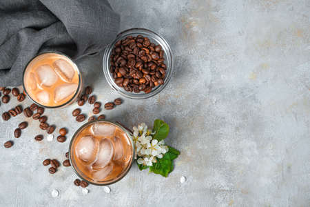 Iced coffee and coffee beans on a gray background. Top view, copy space.