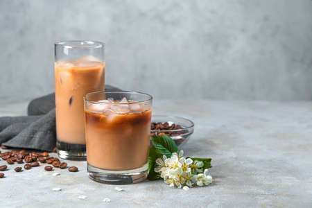 Iced coffee with milk on a gray background with coffee beans. Side view, copy space.