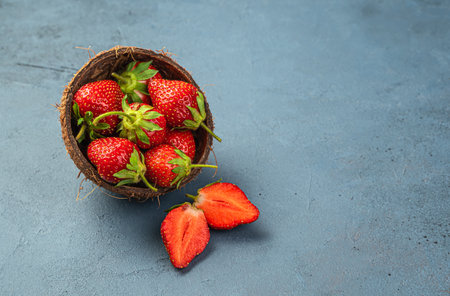 Fresh strawberries in a cup and coconut on a dark background. Side view, copy space.の写真素材