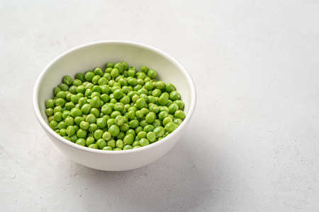 Open peas with a white bowl on a gray background. Side view, space for copying.の写真素材