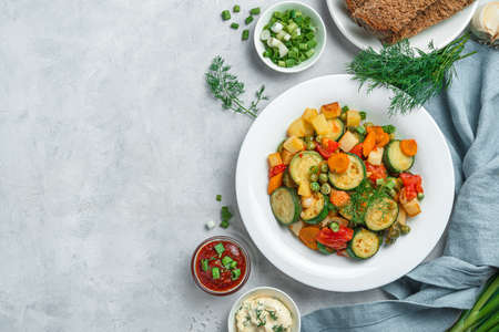 Healthy stewed vegetables in a white plate on a gray background. Top view, copy space.の写真素材