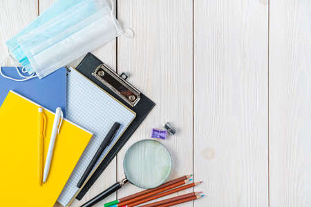 Office supplies and protective masks on a white background. Top view, copy space. Back to school.