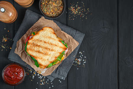 Grilled sandwich with vegetables, ham and cheese on a black background. Top view. Fast food.の写真素材