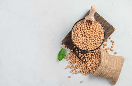 Raw, dried chickpeas in a bowl and a bag on a gray background. Top view, copy space.