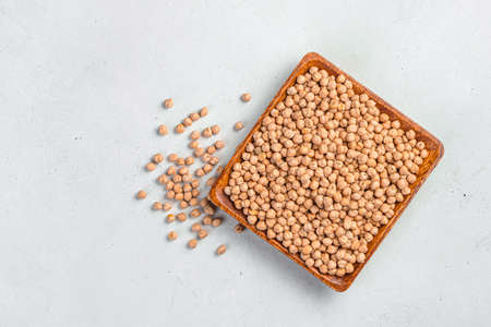 Chickpeas in a wooden, square plate on a gray background with space for copying. Natural, healthy food.の写真素材