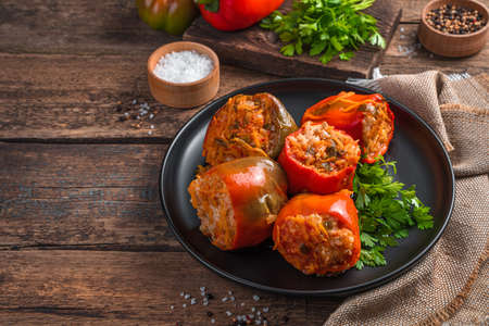 Homemade, stewed Bulgarian pepper stuffed with meat, rice and vegetables on a wooden background. Side view, space for copying.の写真素材
