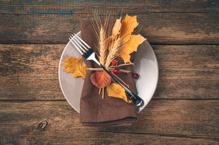 Autumn, culinary background. A plate with a linen serving napkin, a fork and autumn leaves. Top view, copy space.の写真素材