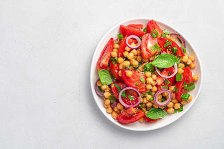Salad with chickpeas and tomatoes on a gray background. Dietary, healthy, vegetarian food. Top view,...