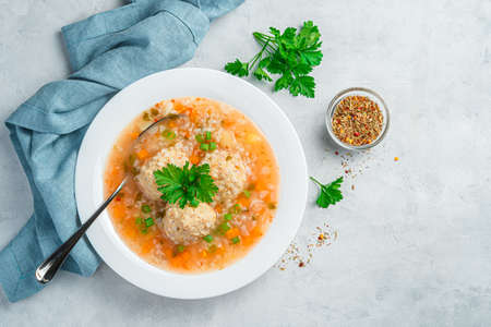 Fresh soup with meatballs and fresh greens on a gray background. Top view, copy space.