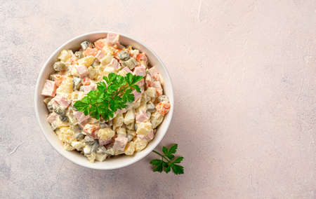 A portion of classic olivier salad with parsley on a light pink background. Side view, copy space.の写真素材
