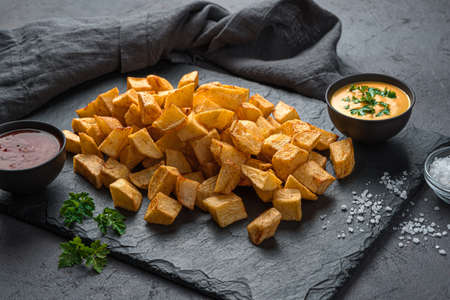 Fried potatoes with spices and sauces, patatas bravas on a black background. Side view, close-up. Tapas, a Spanish snack.の写真素材