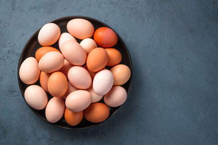 Fresh chicken eggs in a plate on a dark background. Top view, copy space.の写真素材