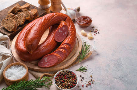 Smoked sausage with spices, garlic and rosemary on a light background. Side view, copy space.