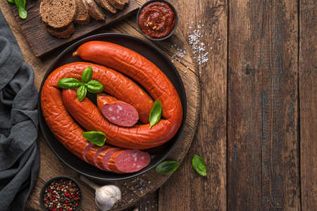Krakow Sausage with fresh basil, spices and garlic on a wooden background. Top view, copy space.の写真素材