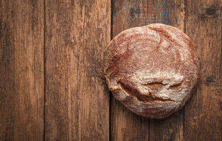 A loaf of fresh rye bread on a wooden table with space for copying. Minimalistic bread background.