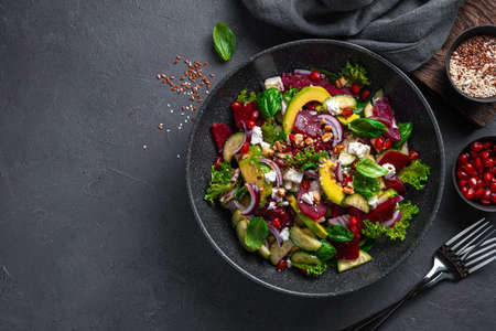 Salad with beetroot, avocado, cucumber and feta seasoned with pomegranate, nuts, flax seeds and sesame seeds. Rich in antioxidants, immune boosting salad.の写真素材