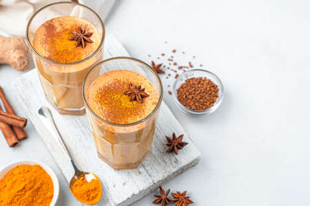Indian latte with turmeric and cinnamon on a light background. Side view, copy space.の写真素材