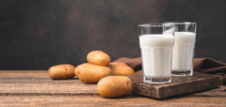 Potato milk in two glasses on the background of potatoes. An alternative to cow's milk. Side view, copy space.の写真素材
