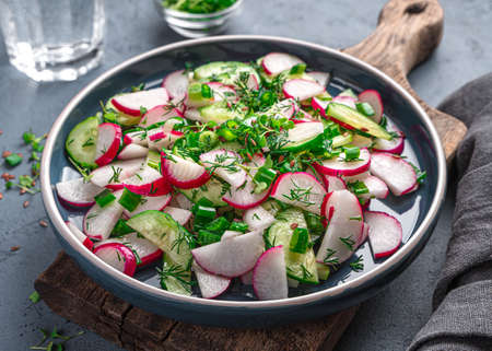 Summer vitamin salad with radish, cucumber, herbs and flax seeds on a graphite background. Side view, close-up. Healthy food.の写真素材
