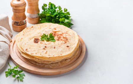 Fresh Indian chapati tortillas with fresh parsley on a gray background. Side view, horizontalの写真素材