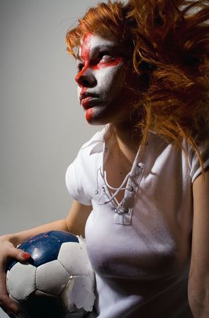 english football makeup girl holding worn soccer ball, looking forwardの写真素材