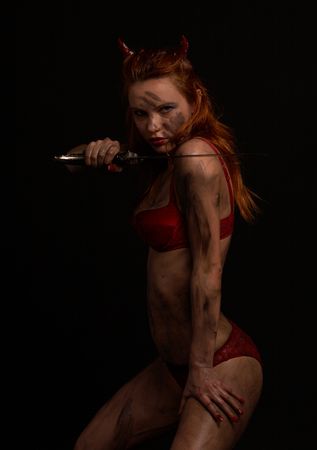 dark red devil girl with a knife over blackの写真素材