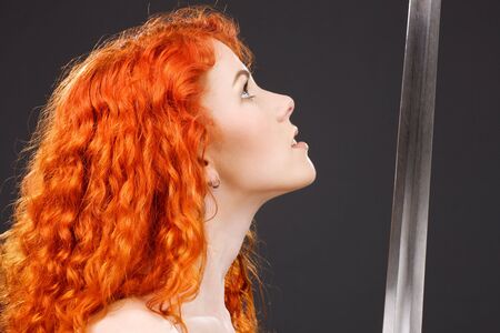 lovely redhead with medieval sword over greyの写真素材