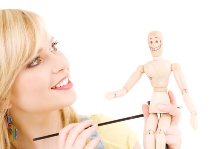happy teenage girl with wooden model dummy over whiteの写真素材