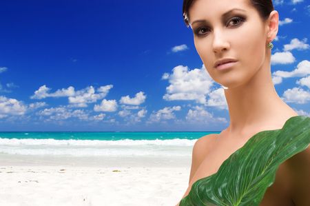 beautiful woman with green leaf on tropical beachの写真素材