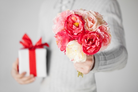 close up of man holding bouquet of flowers and gift box の写真素材