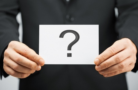 picture of man in suit holding card with question mark
