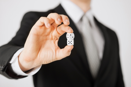 close up of mans hand holding white casino diceの写真素材