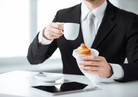 businessman with tablet pc, cup of coffee and croissantの写真素材
