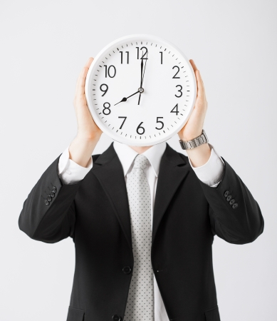 man covering his face with wall clockの写真素材