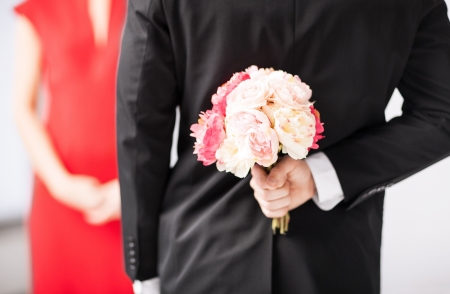 man hiding bouquet of flowers behind his back の写真素材