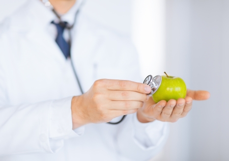 close up of male doctor with green apple and stethoscopeの写真素材