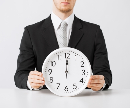 close up of man holding wall clockの写真素材