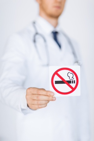 close up of doctor holding no smoking sign in handsの写真素材