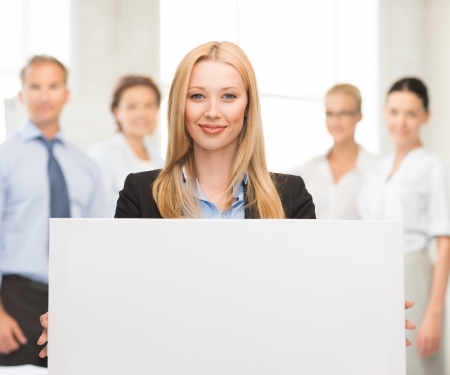 smiling businesswoman with white blank board in officeの写真素材