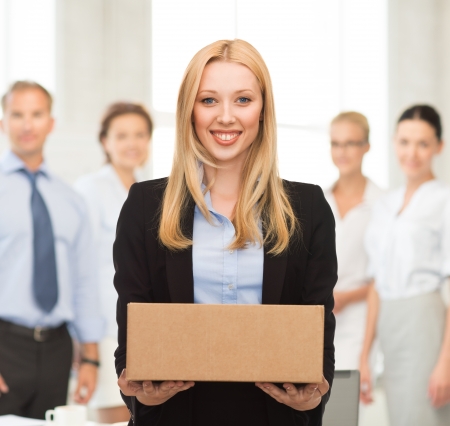 attractive businesswoman delivering cardboard box in officeの写真素材