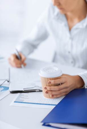 business concept - businesswoman with coffee filling in blank paperの写真素材