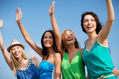 summer holidays and vacation - girls walking on the beach and waivng handsの写真素材