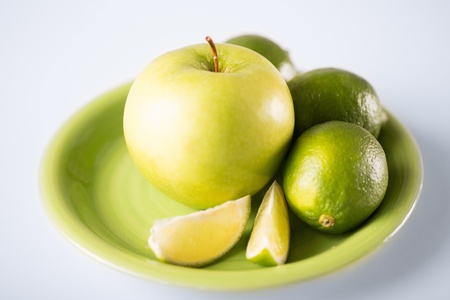 healthy food and cooking concept - green apple with limes in green bowlの写真素材