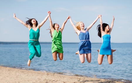 summer holidays and vacation - girls jumping on the beachの写真素材