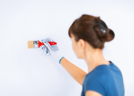 interior design and home renovation concept - woman with paintbrush colouring the wallの写真素材