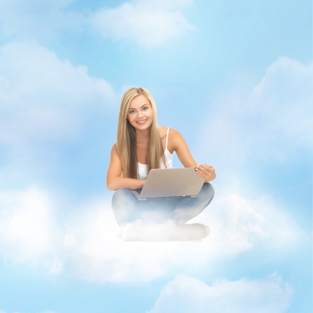 education and technology concept - young woman sitting on the cloud with laptopの写真素材