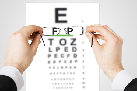 medicine and vision concept - man looking at eye chart through eyeglasses