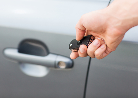 transportation and ownership concept - man with car key outside